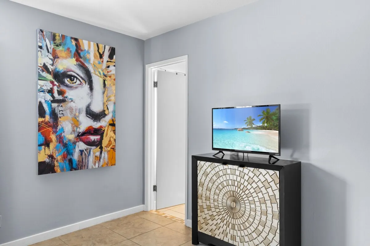 A bright and creative living area decorated with colorful artwork, a wall-mounted TV, and a stylish cabinet. The space feels playful yet contemporary, providing a comfortable spot for children to relax, play games, or watch movies after a day of exploration.